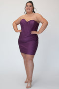 Short fitted purple party dress SC8143 by Sydney's Closet. Front view.  Strapless, exposed boning basque waist and ruched fitted skirt in shimmer stretch knit. Long invisible center back zipper. Availability in black, purple, red, ivory, green and royal. Model in picture is 5'9.