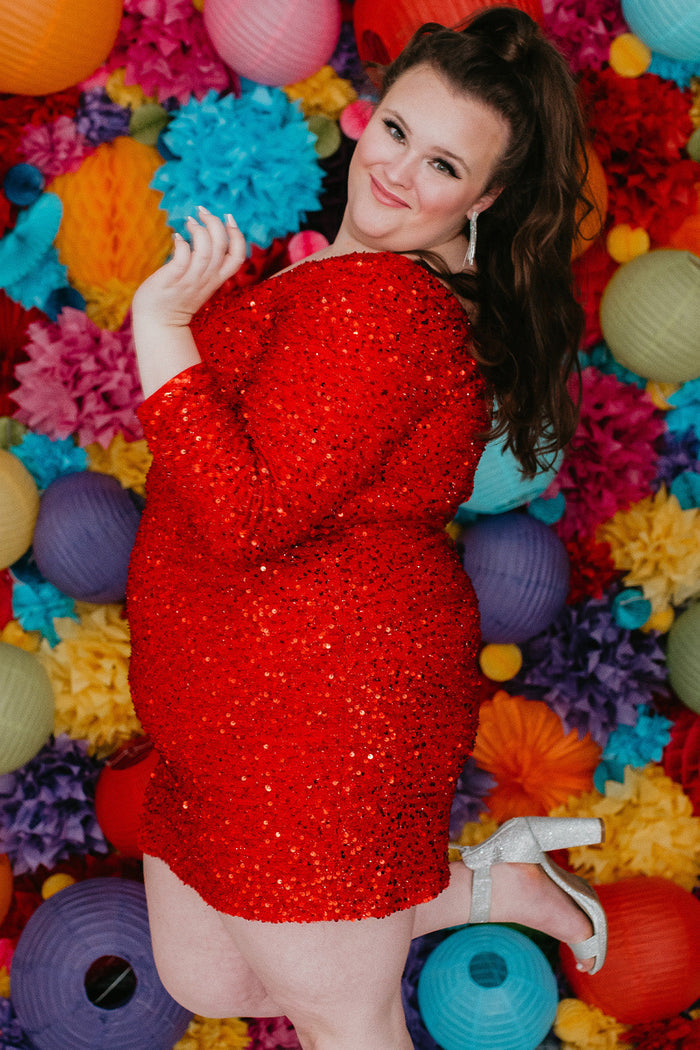 Plus size short sequin party dress with one-shoulder long sleeve, slit and center back zipper. Fabulous jewel tone colors: Hunter Green, Onyx Black, Ruby Red, Pearlescent White or Sapphire Blue. Style SC8112 by Sydney's Closet