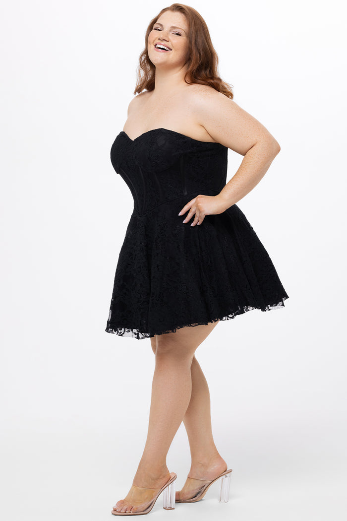 Celebrations by Sydney's Closet Style CE2612 in black. 

Plus size strapless black short mini party dress with sweetheart neckline, exposed corset boning on bustier bodice and mini skirt in all over stretch lace.