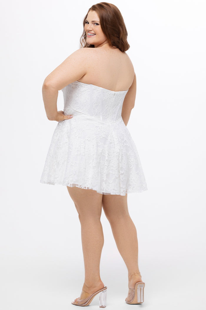 Celebrations by Sydney's Closet Style CE2612 in white. 

Plus size strapless white short mini party dress with sweetheart neckline, exposed corset boning on bustier bodice and mini skirt in all over stretch lace.