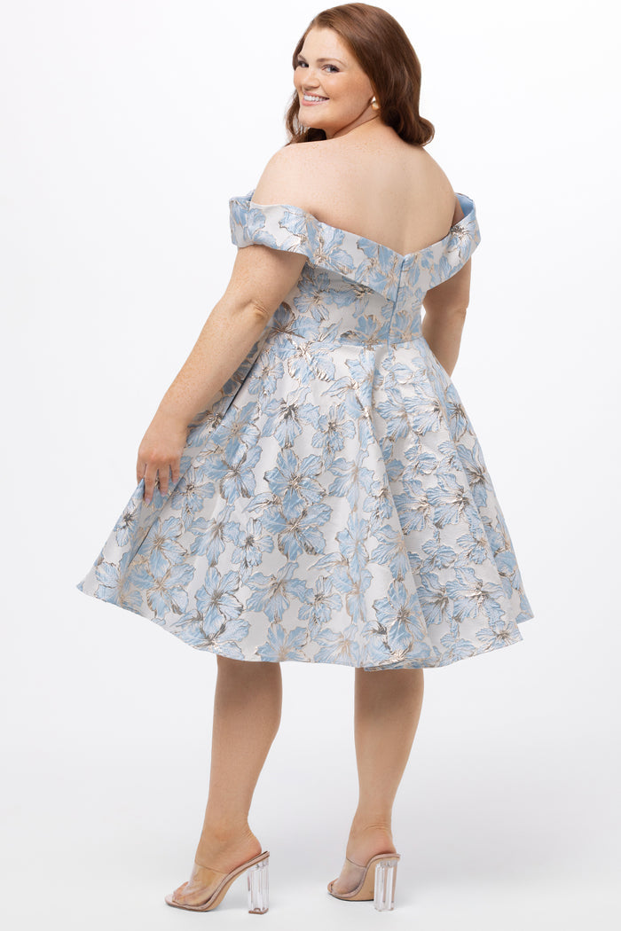 Celebrations by Sydney's Closet CE2610 in Light Blue Floral. 

Plus size knee-length party dress in metallic light blue floral brocde print. Off-the-shoulder neckline, natural waistline and A-line skirt with pockets.