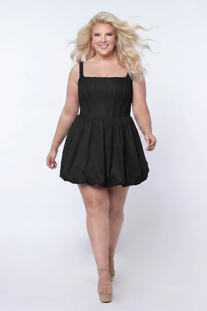 Plus-size model wearing a black sleeveless taffeta mini dress with a square neckline, structured corset-inspired bodice with exposed boning, and voluminous bubble hem skirt. She is styled with long flowing blonde hair, drop earrings, and nude platform ankle-strap heels, walking toward the camera against a light gray studio background. Front view.

Sydney's Closet SC8166 in black