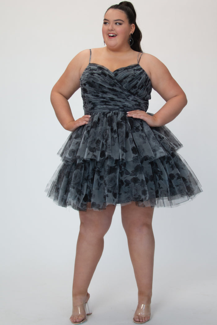Tiered floral short party dress, SC8151 by Sydney's Closet. Front view. In the color Black/floral. Floral tulle fabric with a satin lining. Fully pleated bodice, sweetheart neckline, double spaghetti straps and a two-tiered skirt. Long invisible center back zipper. Available in blue/floral and black/floral sizes 14-32. 
Model is 5'9.