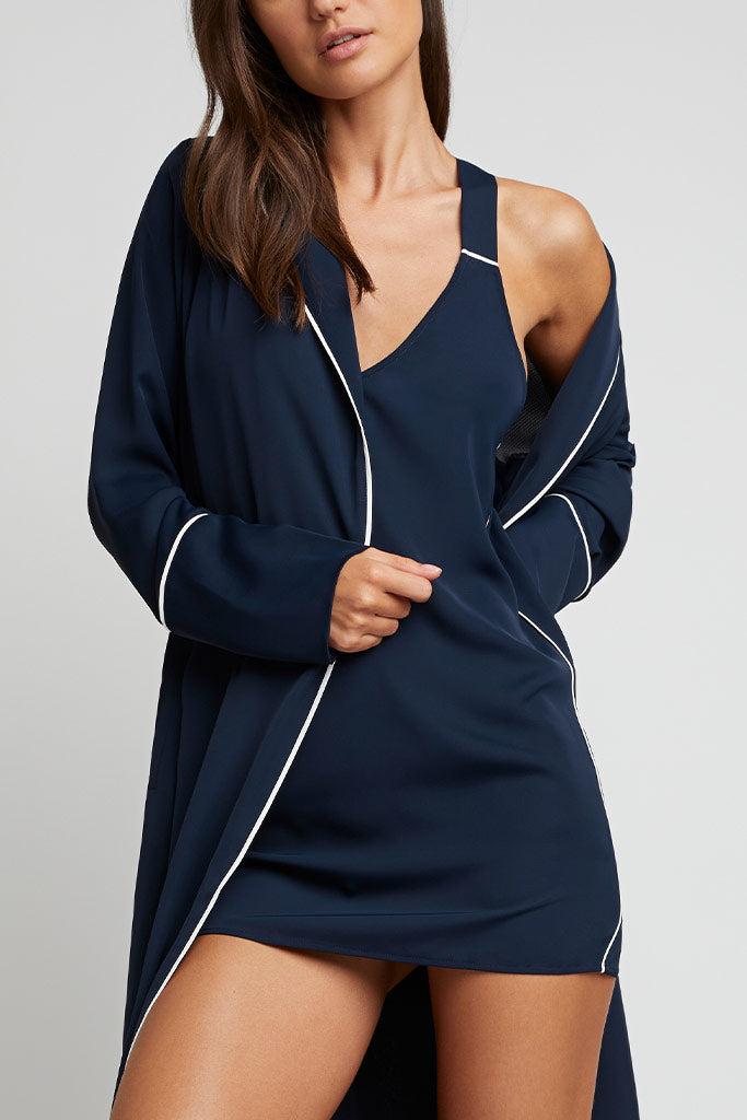 Navy robe worn open with white piped trim along collar and sleeves