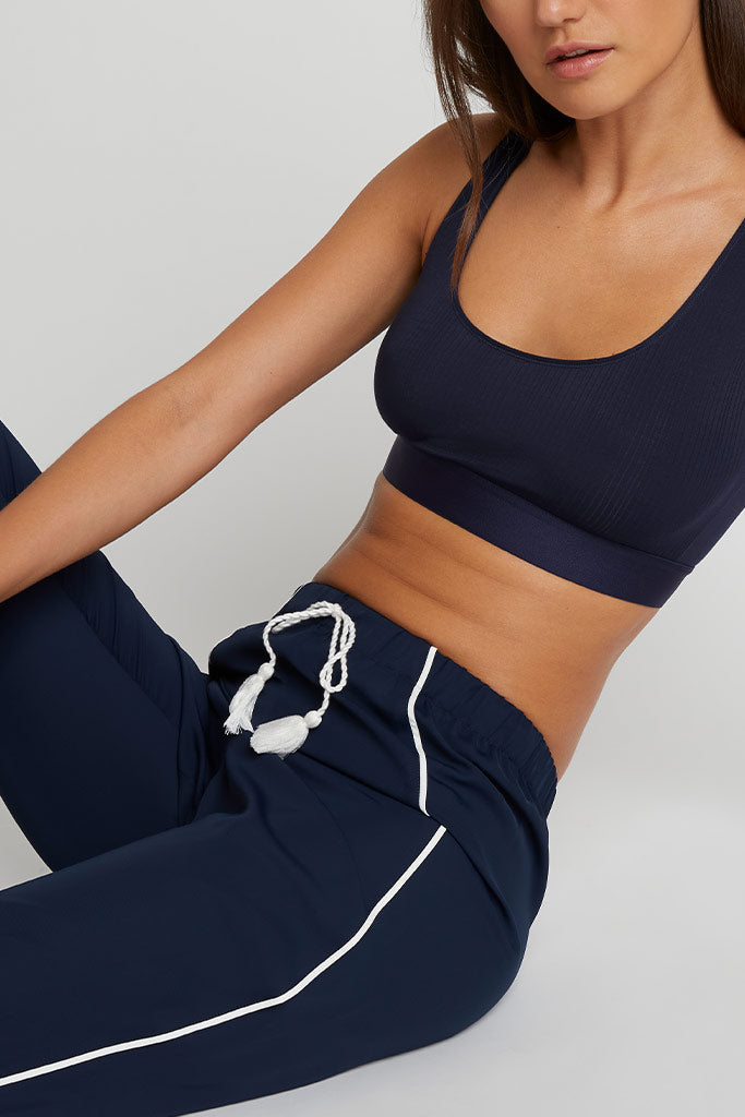 Navy jogger pants close-up: drawstring waistband with white tassels, side stripe
