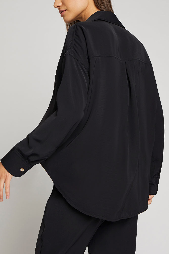 Black long-sleeve button-up shirt with relaxed fit and curved hem, side view