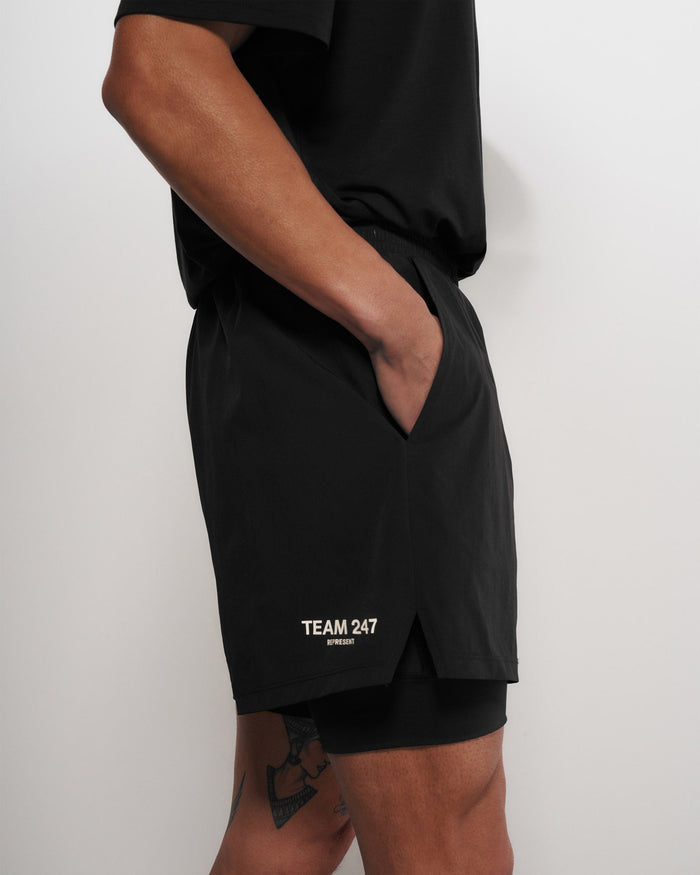 Man wearing black 2-in-1 shorts on a plain white background | Team 247 2-In-1 Shorts in Black | Shorts with inside leggings and zip pockets | 247 Shorts | Represent Clo