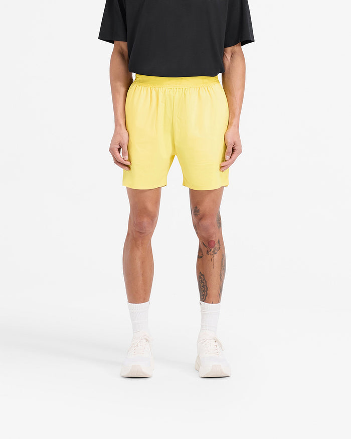 Man wearing yellow training shorts on a plain white background | Team 247 Fused Shorts in Lemon | Gym shorts with internal drawcords and quick drying fabric | 247 Shorts | Represent Clo