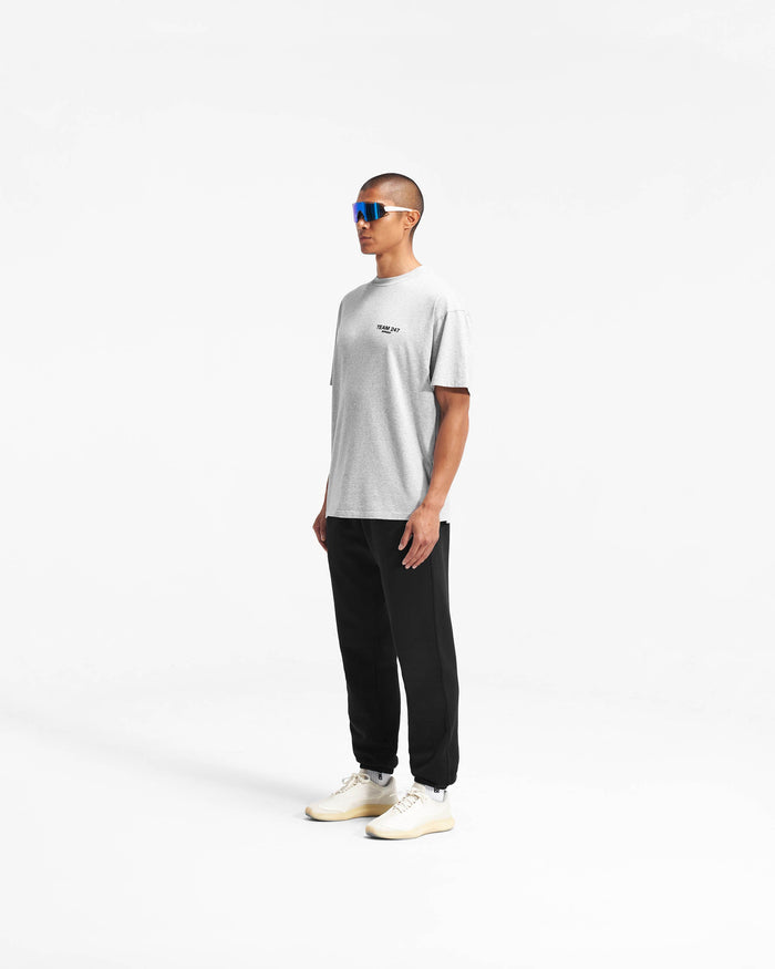 Man wearing an oversized grey t-shirt on a plain white background | Team 247 Oversized T-Shirt in Ash Grey | Lightweight quick-dry gym t-shirt with Team 247 branding | 247 T-Shirts | Represent Clo