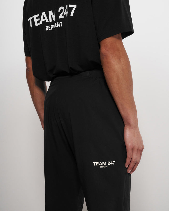 Man wearing black training pants on a plain white background | Team 247 Training Pant in Black | Training pants with zip pockets and cuffs | 247 Pants | Represent Clo