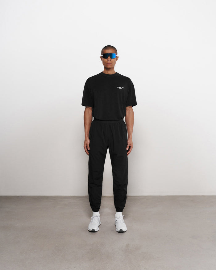 Man wearing black training pants on a plain white background | Team 247 Training Pant in Black | Elastic waistband with zip pockets | 247 Pants | Represent Clo
