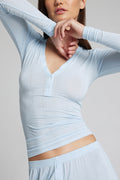 Light blue ribbed henley top with V-neck, button placket, and cropped hem